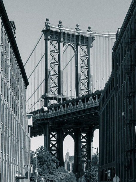 The Empire State Building in the arch between the supports of the Manhattan Bridge, framed by the old buildings of DUMBO