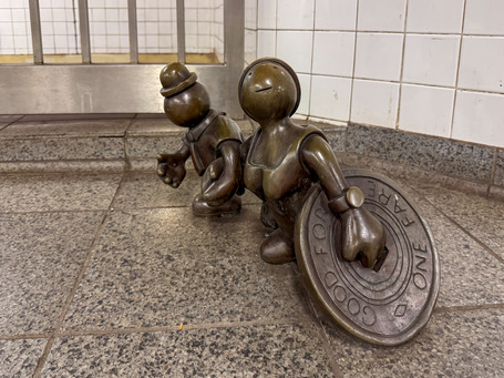 Two small copper figures in the metro station on 14th Street in Manhattan