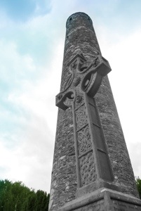 Ein Round Tower in Glendalough mit Keltenkreuz davor