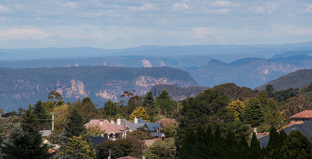 Im hintergund die Berge. In der Mitt und dem Vordergund Häuser der Stadt Katoomba